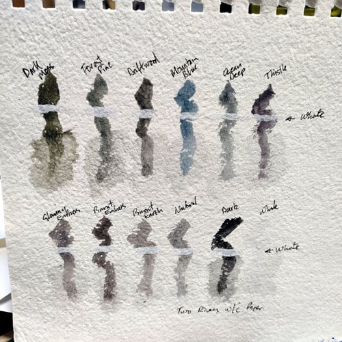 Paint swatches of tinted charcoal paint pan set on extra textured paper from sketchbook